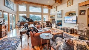 A spacious living room with a large window, a fireplace, and a variety of seating arrangements. - Pikes Peak Place: Relaxing Oasis w/Mtn Views (Colorado Springs)