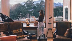A spacious living room with large windows, a piano, and a cozy seating area. - Pikes Peak Place: Relaxing Oasis w/Mtn Views (Colorado Springs)