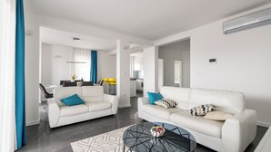Een moderne woonkamer met twee witte banken, een zwarte salontafel en een kamerkleed met een patroon.