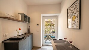 Une cuisine compacte avec un coin repas, un mur en pierre et une vue sur l’extérieur.
