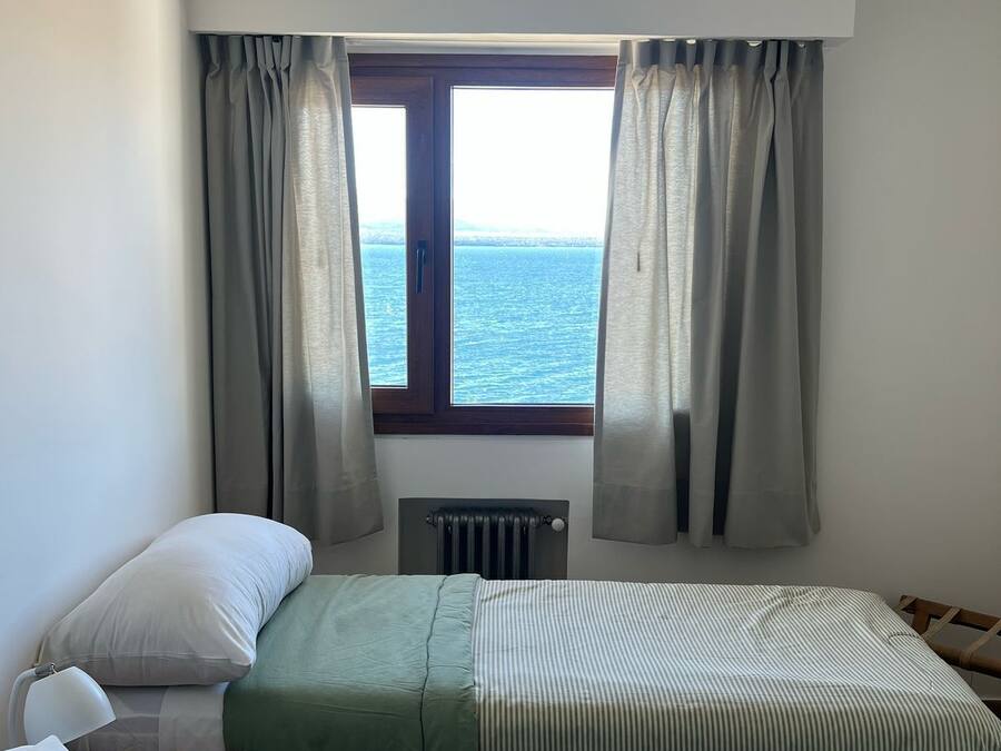 Quarto com duas camas, um radiador e uma janela com cortinas.