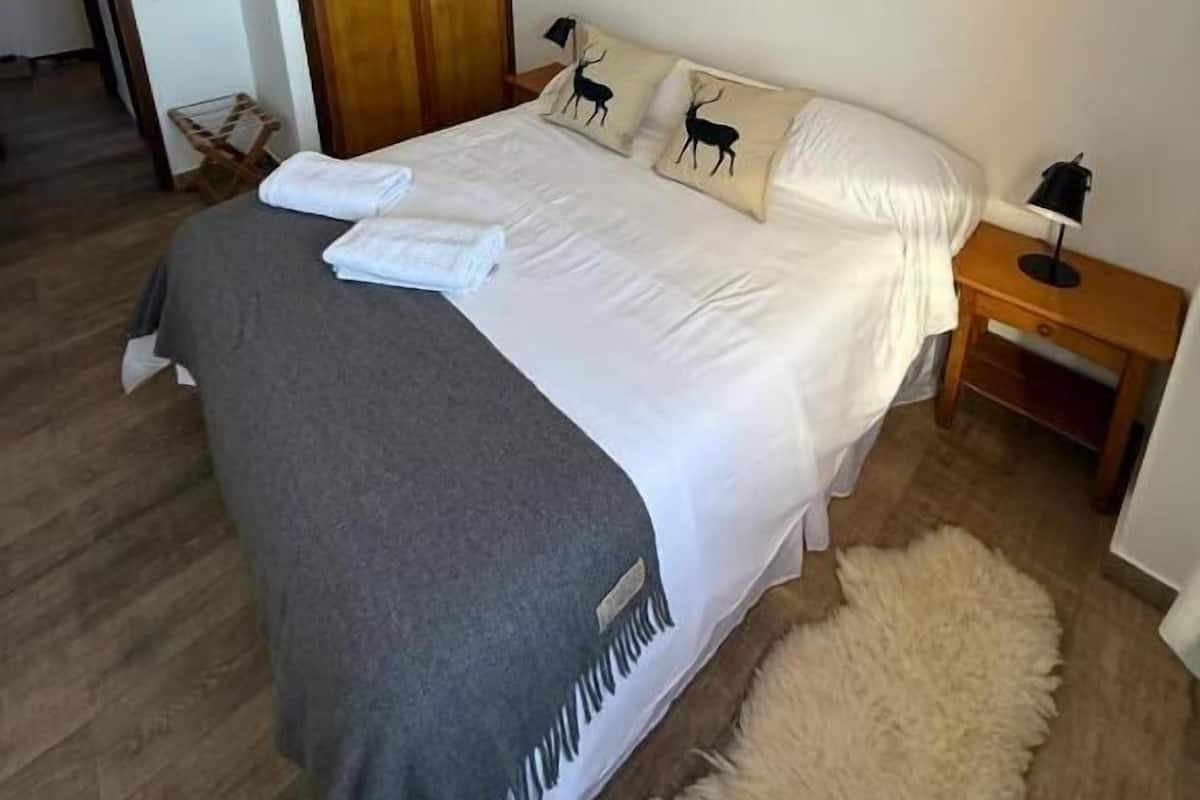 Un dormitorio con cama, un armario de madera, una mesita de noche y una alfombra mullida.