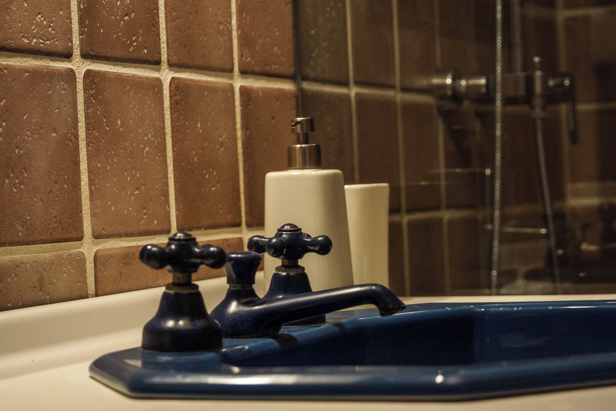 Un bagno con una vasca, due rubinetti e un erogatore di sapone.