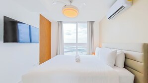 A hotel room with a bed, a TV, a ceiling fan, and a window with a view. - The Sands by Wynwood House (Panama City)