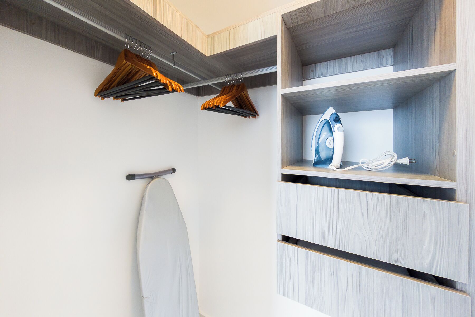 A modern bathroom with a wooden vanity, a hanging shower curtain rod, and a towel rack.