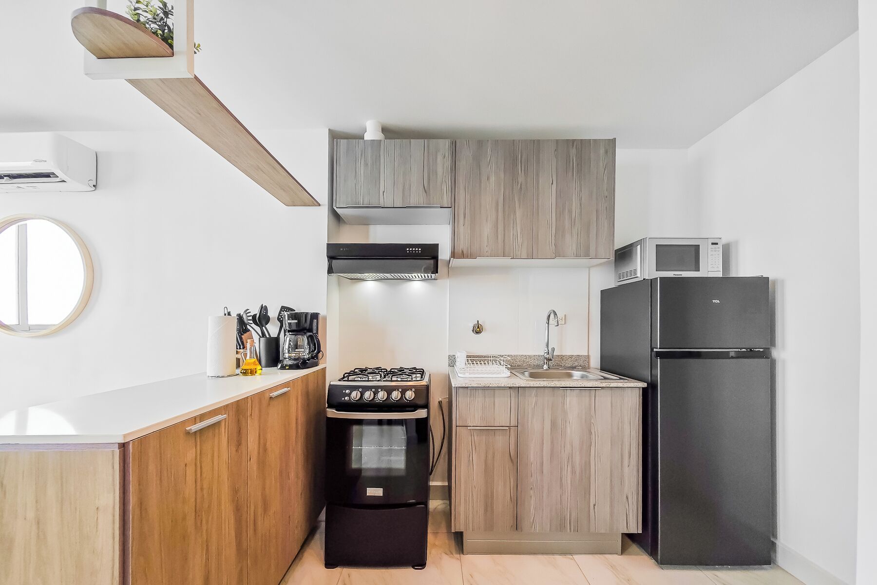 A compact kitchen with a gas stove, oven, microwave, and refrigerator.