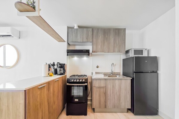 Una cocina compacta equipada con estufa a gas, horno, microondas y refrigerador.