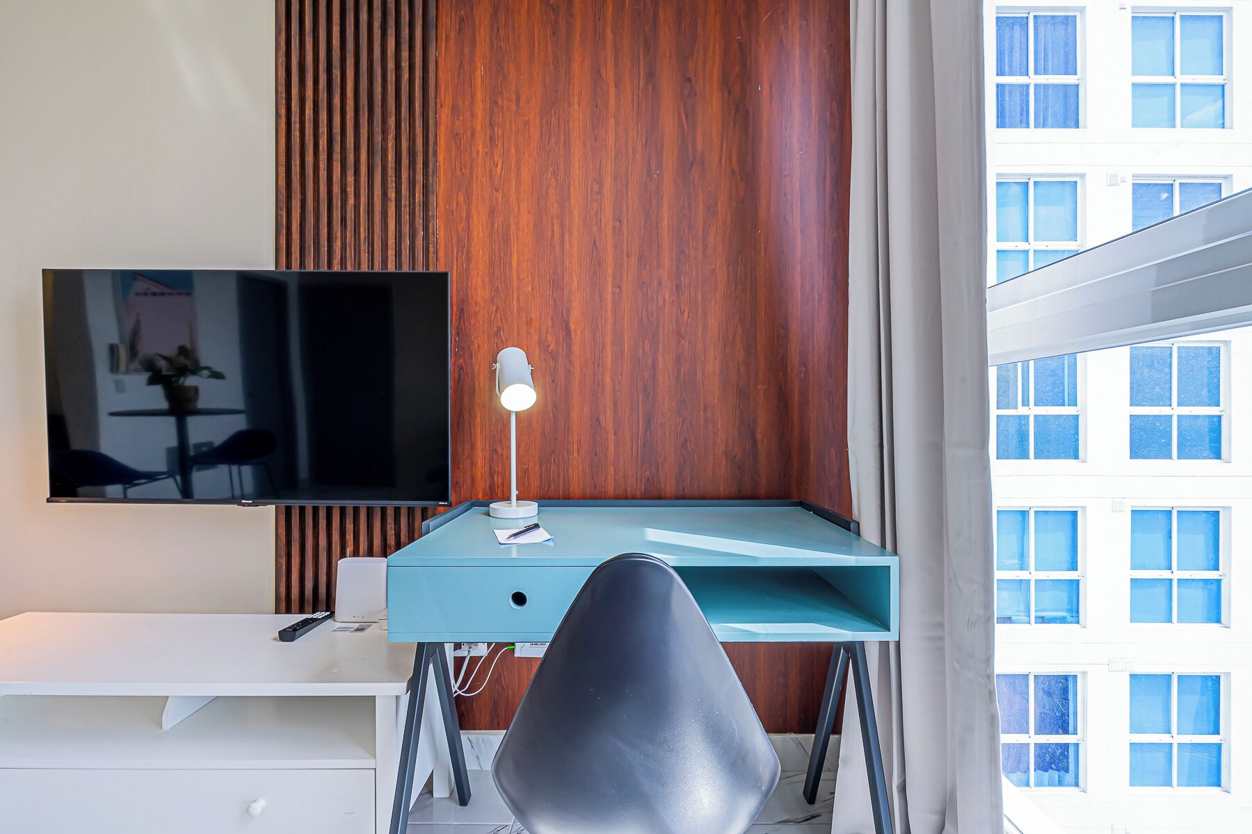 A modern office space with a desk, chair, and a mounted TV.