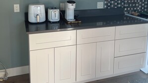 A kitchen with white cabinets, a black countertop, and a window with a view of the outdoors.