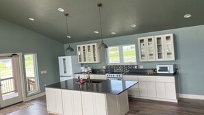 A kitchen with a central island, white cabinets, a stove, and a microwave.