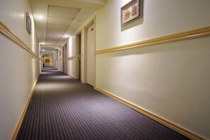 A hotel hallway with carpeted floors, doors on both sides, and framed pictures on the walls. - Jinqilin Hostel (Shanghai Waigaoqiao Free Trade Zone) (Shanghai)