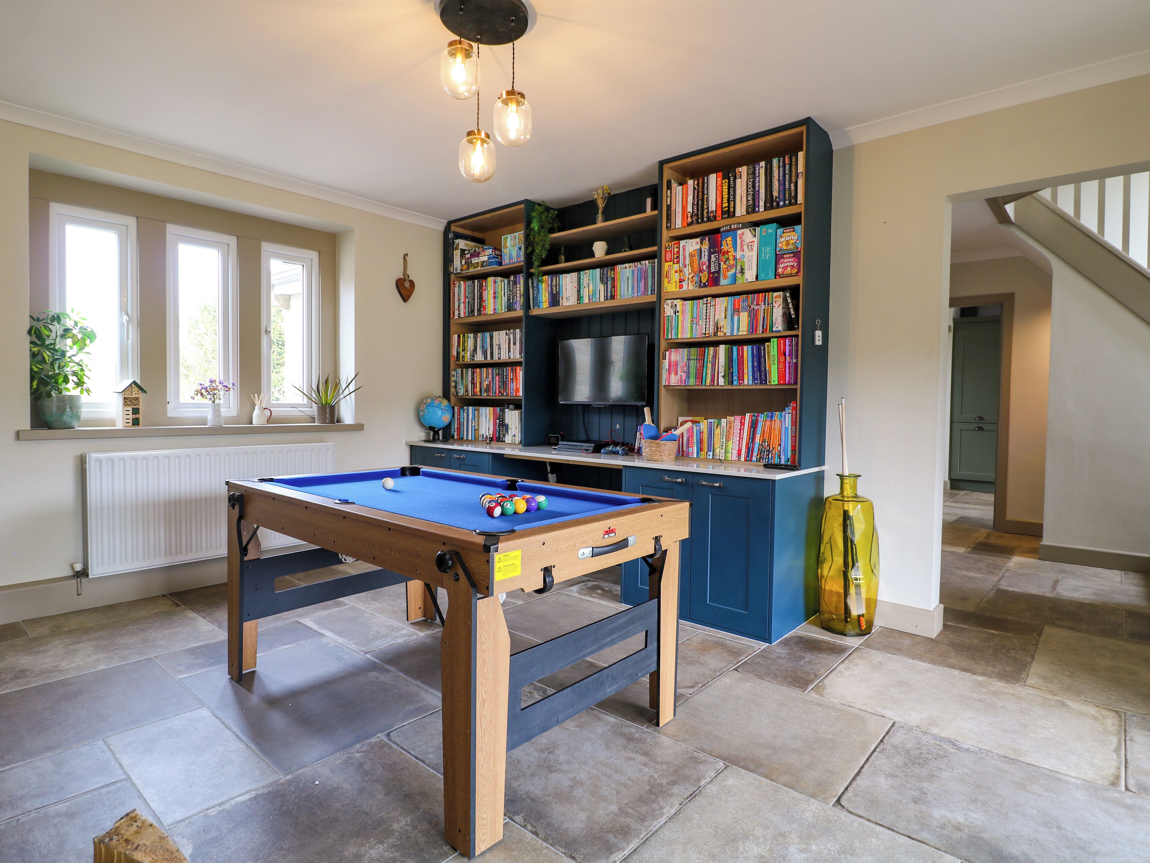 Una habitación con mesa de billar, estanterías, un globo terráqueo y televisor.