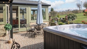 A patio area with a hot tub, outdoor furniture, and a stone wall in the background. - Cherry Tree Farm (Chesterfield)