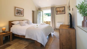 A bedroom with a large bed, a bedside table with a lamp, a television, and a potted plant. - Cherry Tree Farm (Chesterfield)
