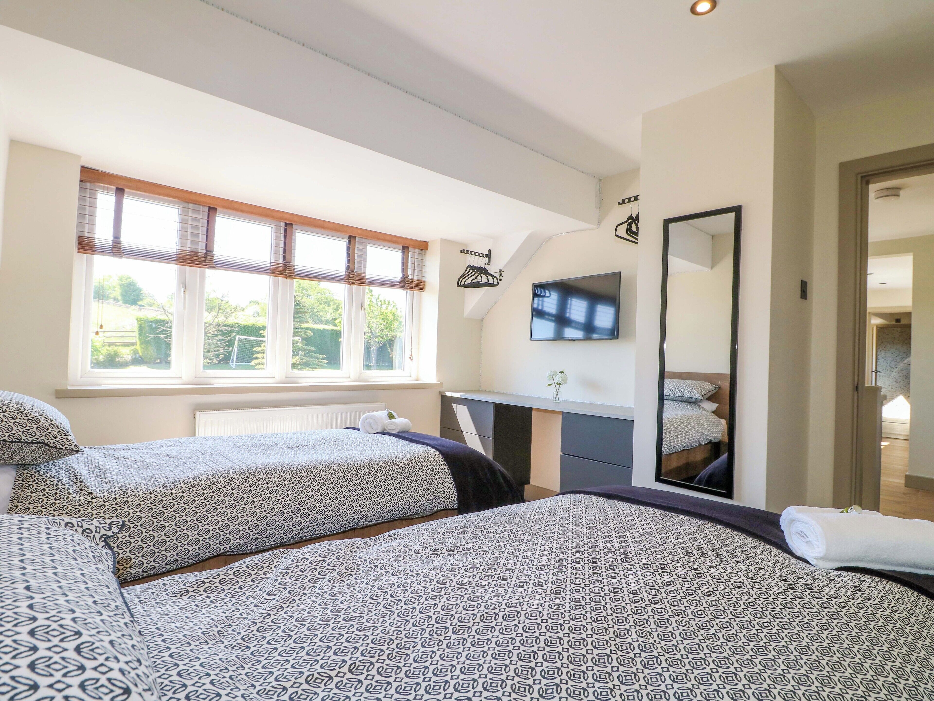 Habitación con dos camas, un televisor y una ventana con persianas.