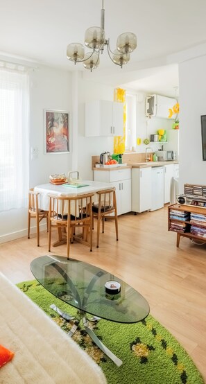 A modern kitchen with white cabinets, a dining area with a glass table, and a chandelier. - Vintage, 10 min from Disneyland -30 min from Paris- 50m from train station - 30min from CDG airport (Esbly)