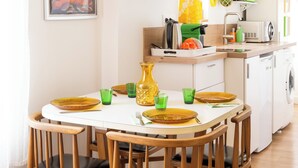 Un comedor con una mesa blanca, sillas de madera y platos amarillos.