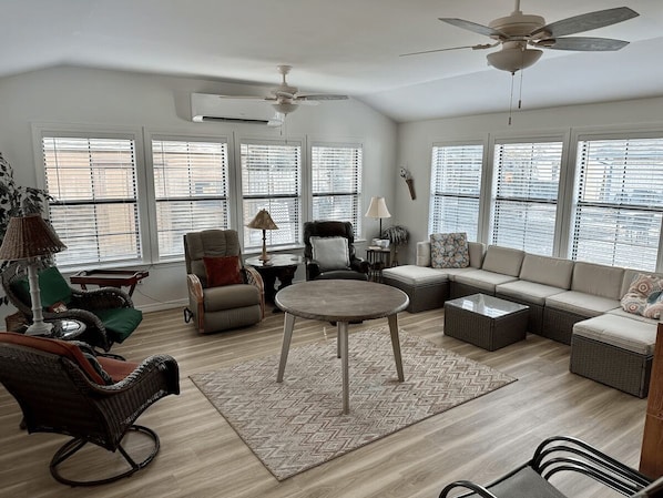 A spacious living room with a round coffee table, sofas, and a ceiling fan.