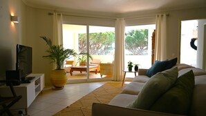 A living room with a sofa, TV, and potted plants. - Jardins do Golfe at Vale do Lobo (Loulé)