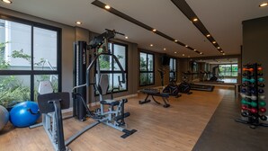 Una palestra con attrezzi per l'allenamento, ampie finestre e pavimento in legno.