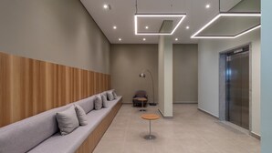 Un'area d'attesa moderna con una panca allungata, un tavolino e una lampada.