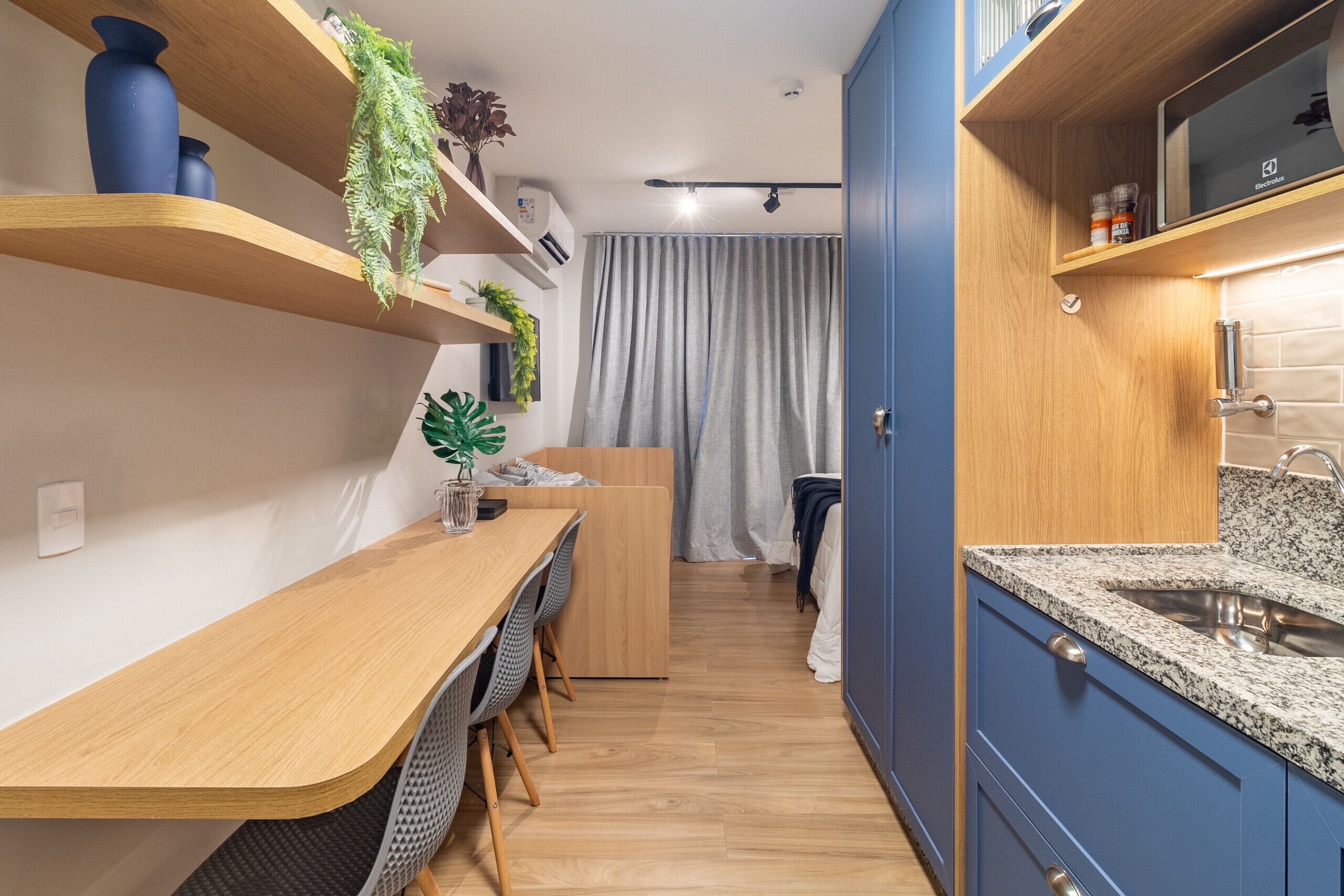 A compact kitchen with wooden countertops, a built-in sink, and blue cabinets.