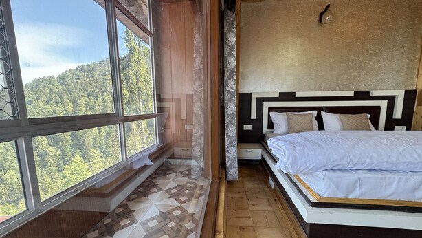 A bedroom with a large window, a bed, and a patterned floor. - Nature Heaven Homestay (Shimla)