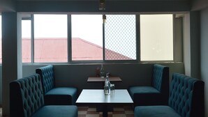 A room with a high ceiling, a round table with three glasses, and a bench seating area. - Nature Heaven Homestay (Shimla)