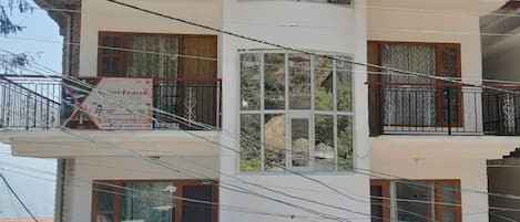Un edificio de varios pisos con balcones, ventanas amplias y un cartel que anuncia una 'Exención de Impuestos sin Depósito'.