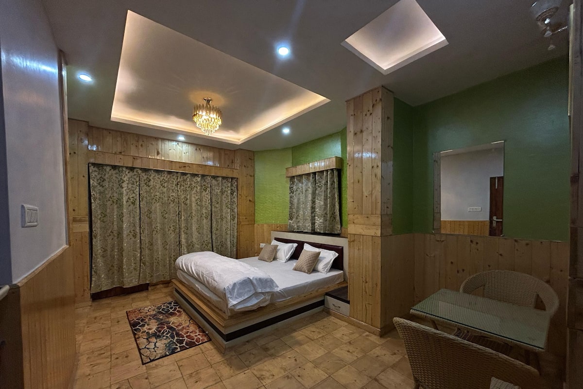 A bedroom with a bed, a small table, and a chair.