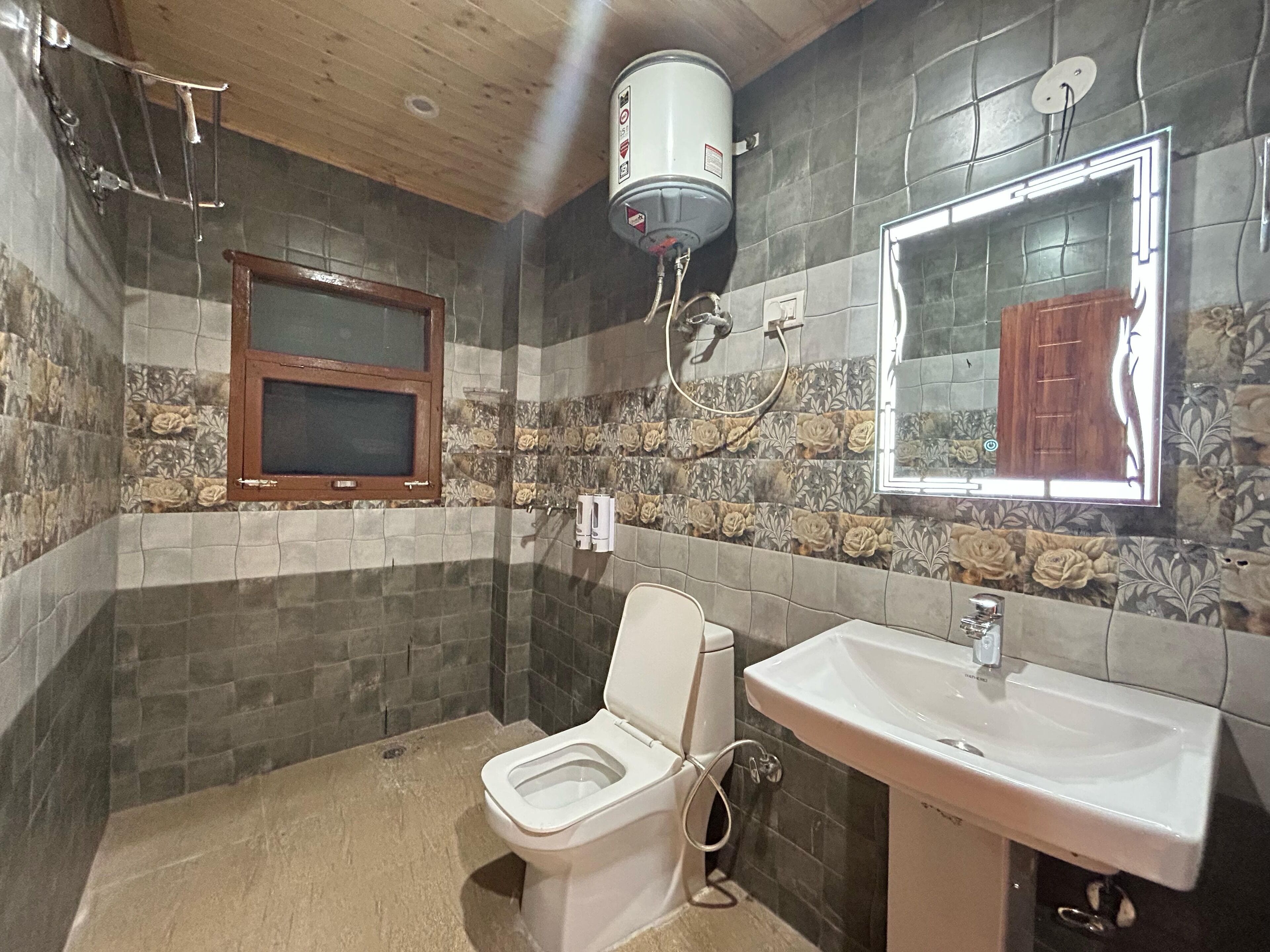 A bathroom with a toilet, sink, and a shower with a water heater.
