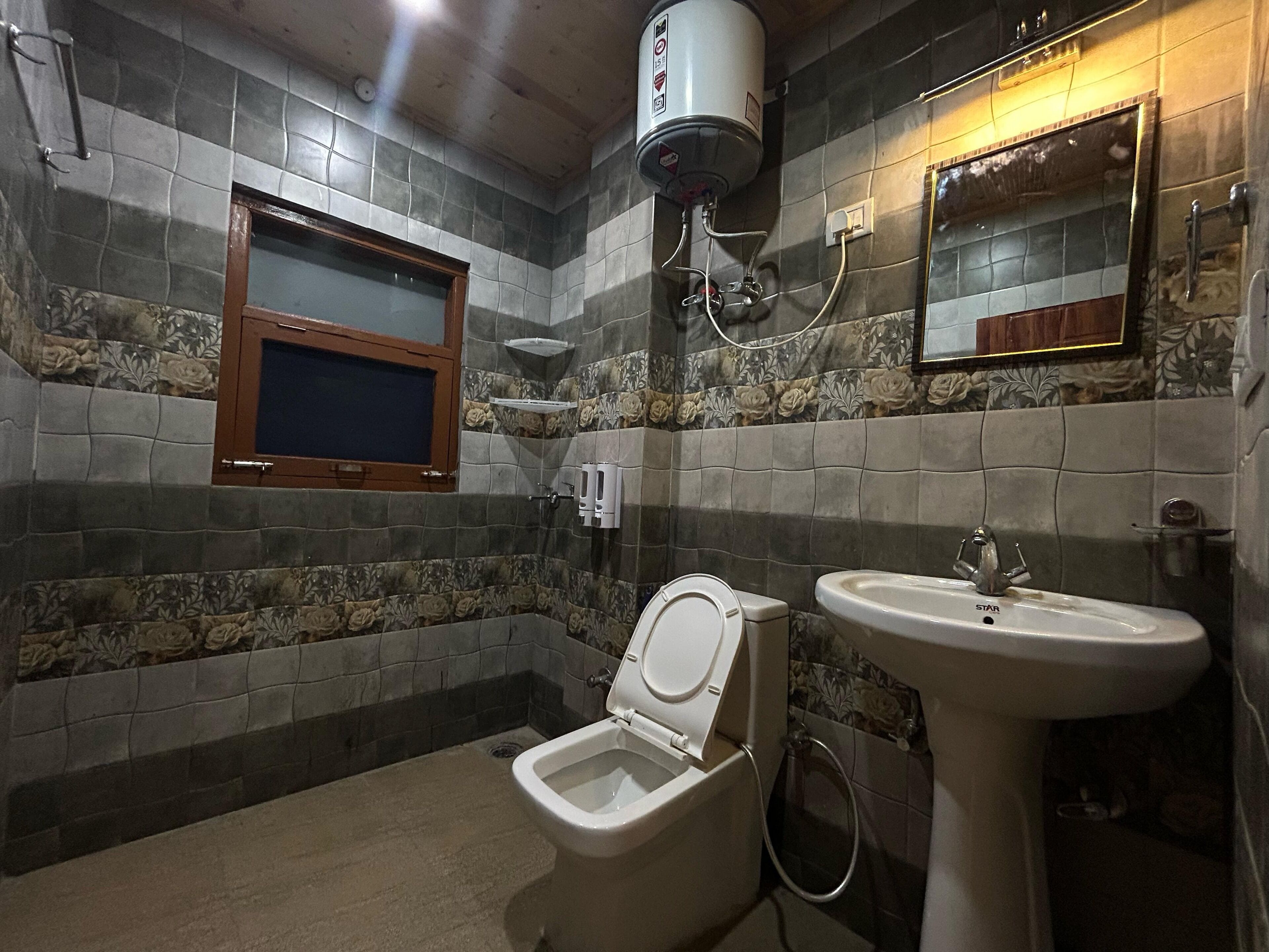 A bathroom with a toilet, bidet, sink, and a water heater mounted on the wall.