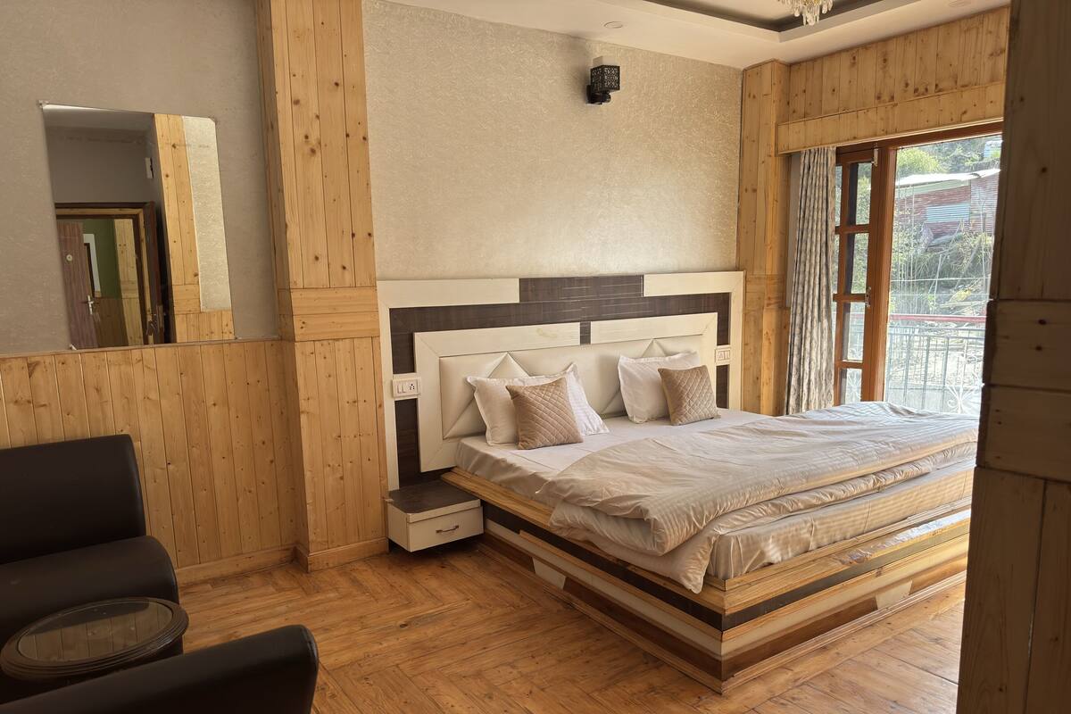 A wooden-paneled room with a bed, a small bedside table, and a chair.