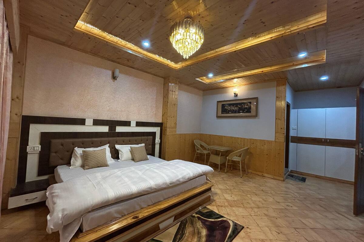 A bedroom with a large bed, wooden ceiling, and a chandelier.