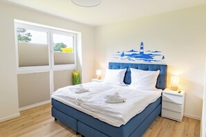 Una camera da letto con un letto, comodini, una finestra con persiane e un murale raffigurante un faro.