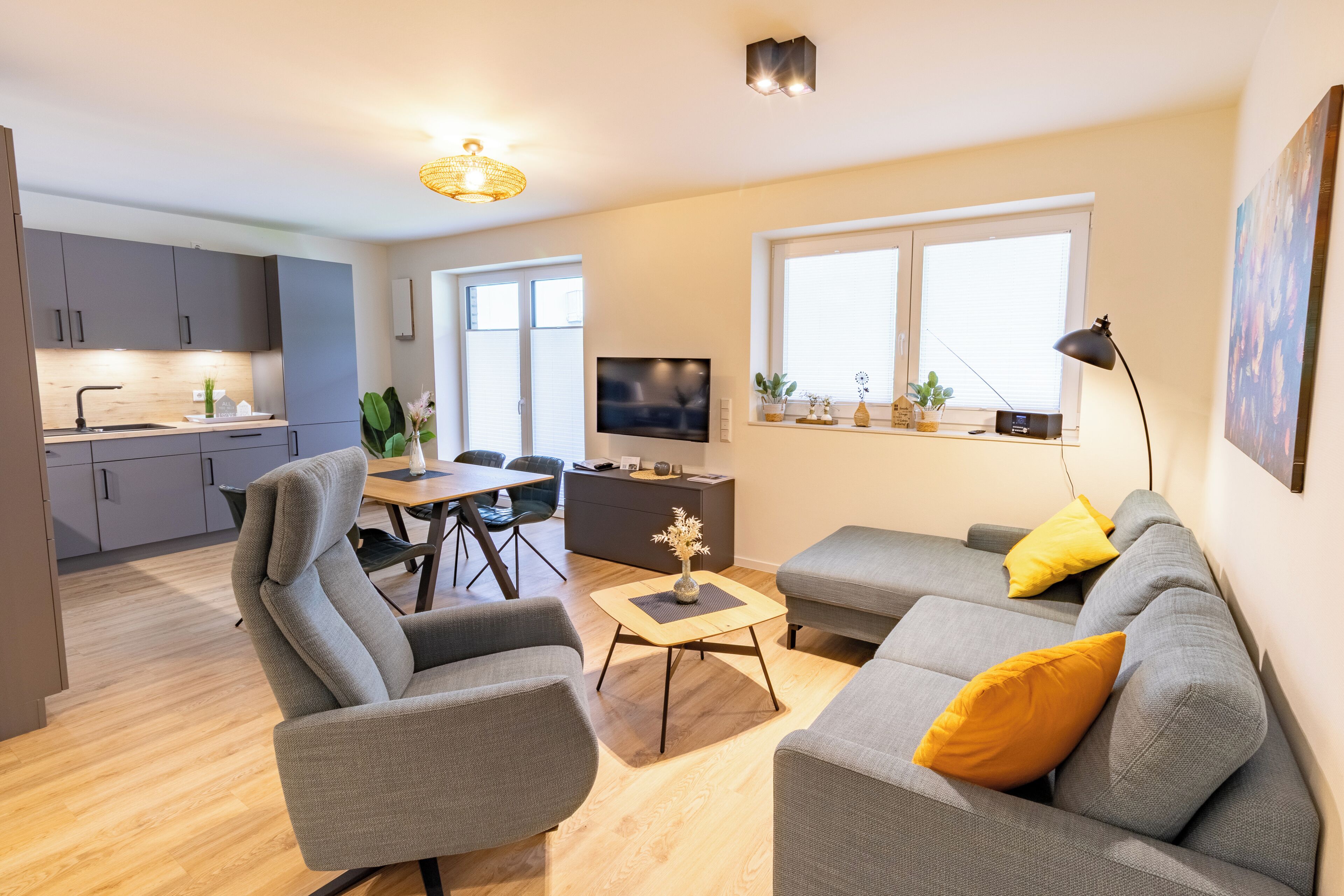 Ein modernes Wohnzimmer mit grauem Sofa, einem Couchtisch und einem Fernseher.
