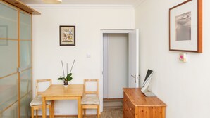 A dining area with a wooden table and chairs, a potted plant, a cabinet, and a framed picture on the wall.