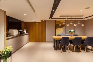 A modern dining area with a wooden table and chairs, a kitchen counter, and pendant lighting. - Guangzhou Zhujiang New Town Homeinn Selected Hotel (Guangzhou)