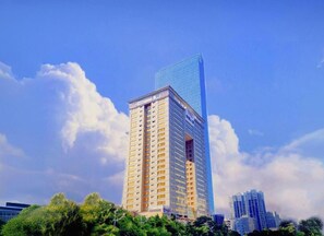A high-rise building with a modern glass facade and a traditional structure beneath it.
