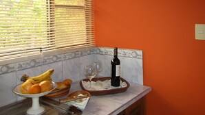A kitchen with a fruit bowl, wine glasses, and a bottle on the counter.