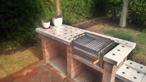 An outdoor brick barbecue grill with a flat top and a chimney.