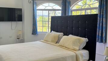 A bed with a quilted headboard, a bedside table, and a wall-mounted TV.