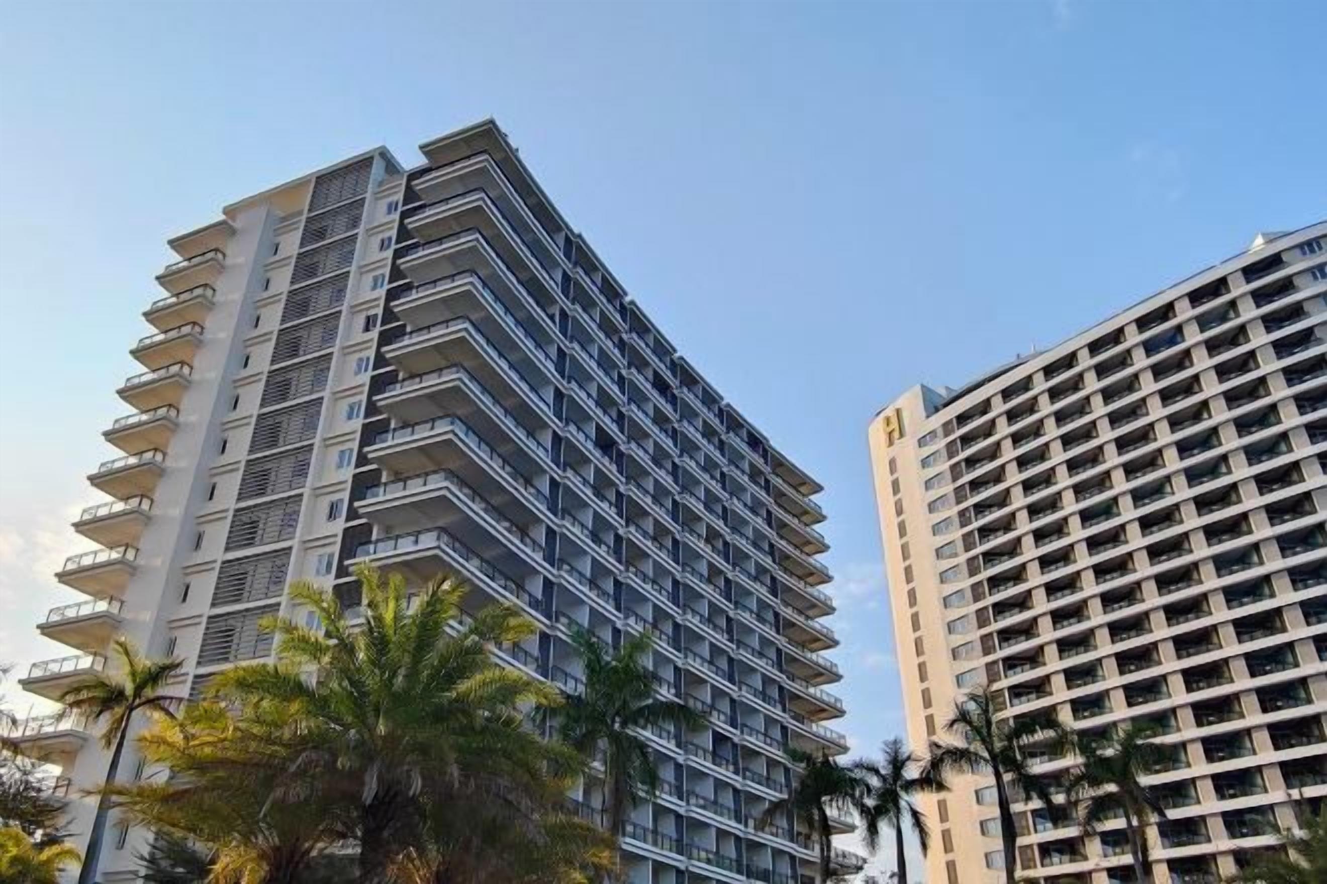 A high-rise building with multiple balconies and a clear sky.