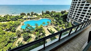A hotel with a pool surrounded by palm trees and a view of the ocean. - Huidong Xunliao Bay New Coast Scenic Hotel (Haigongyuan Leisure Beach) (Huidong)