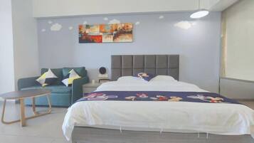 Quarto com cama, sofá, uma mesinha e um quadro na parede.