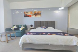 Une chambre à coucher avec un lit, un canapé, une petite table et un mur orné d’un tableau.