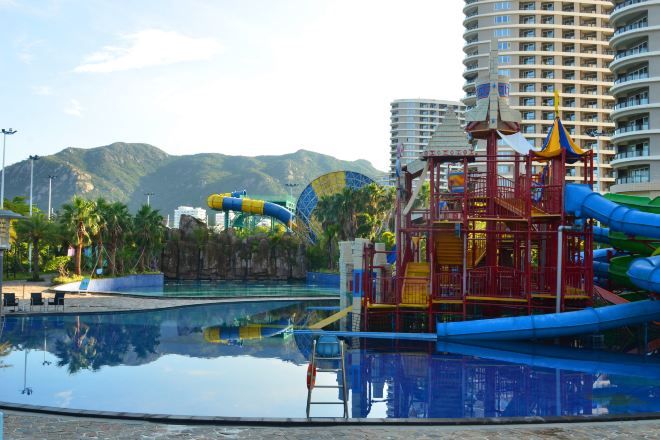 Un área de parque acuático con piscina, toboganes y una estructura de juegos.