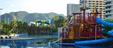 Un área de parque acuático con piscina, toboganes y una estructura de juegos.