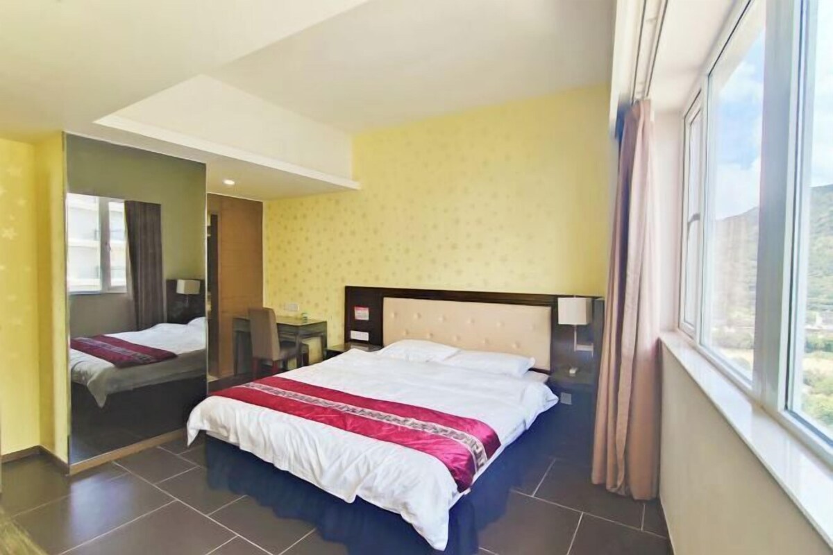 Une chambre d’hôtel avec un grand lit, un miroir, un bureau et une fenêtre avec des rideaux.