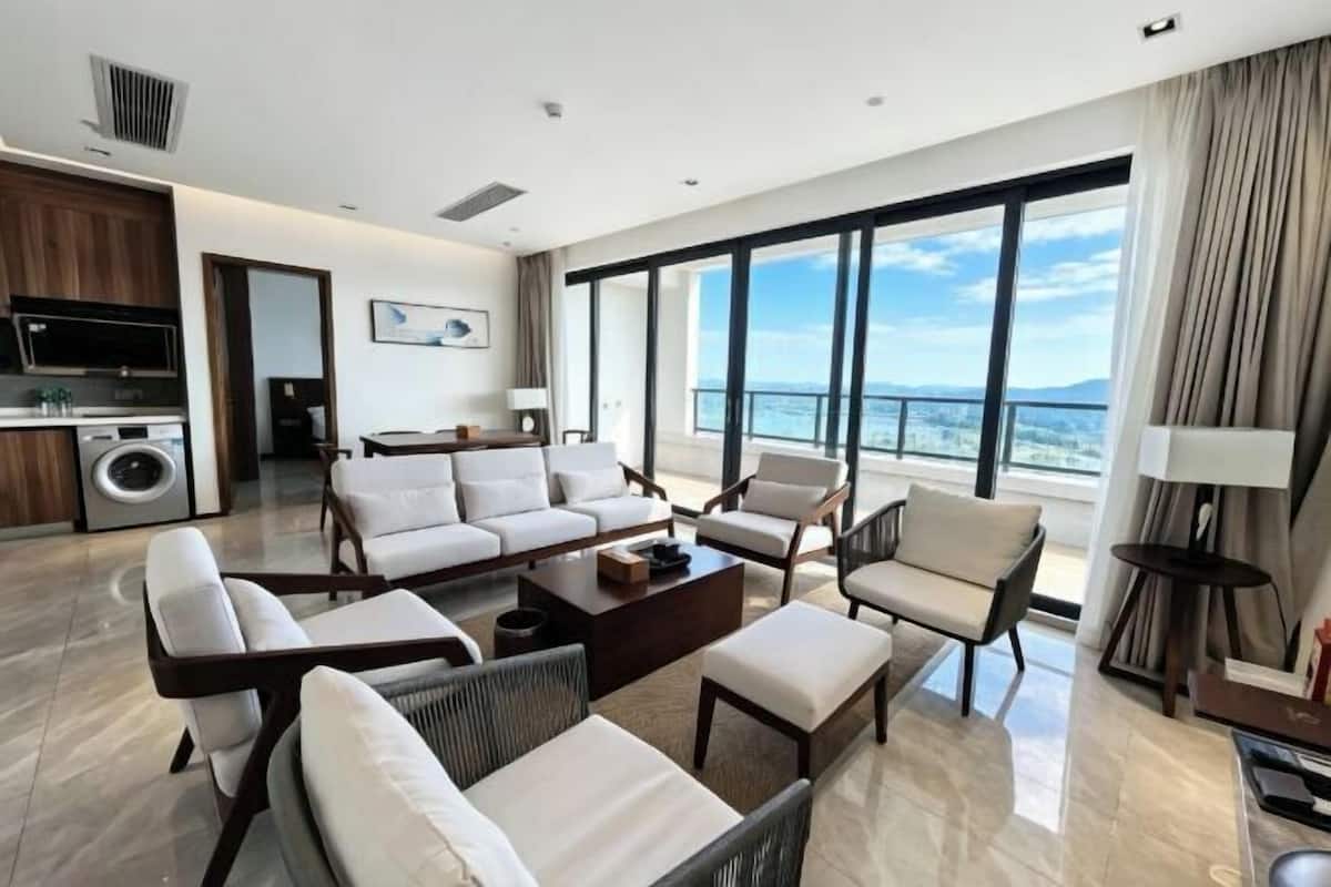 A modern living room with a sofa, chairs, a coffee table, and a view of the ocean.